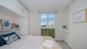 Un dormitorio moderno con una cama grande, una ventana con vistas y una decoración minimalista.