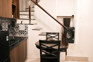 Cocina compacta con comedor, lavadora y escalera.