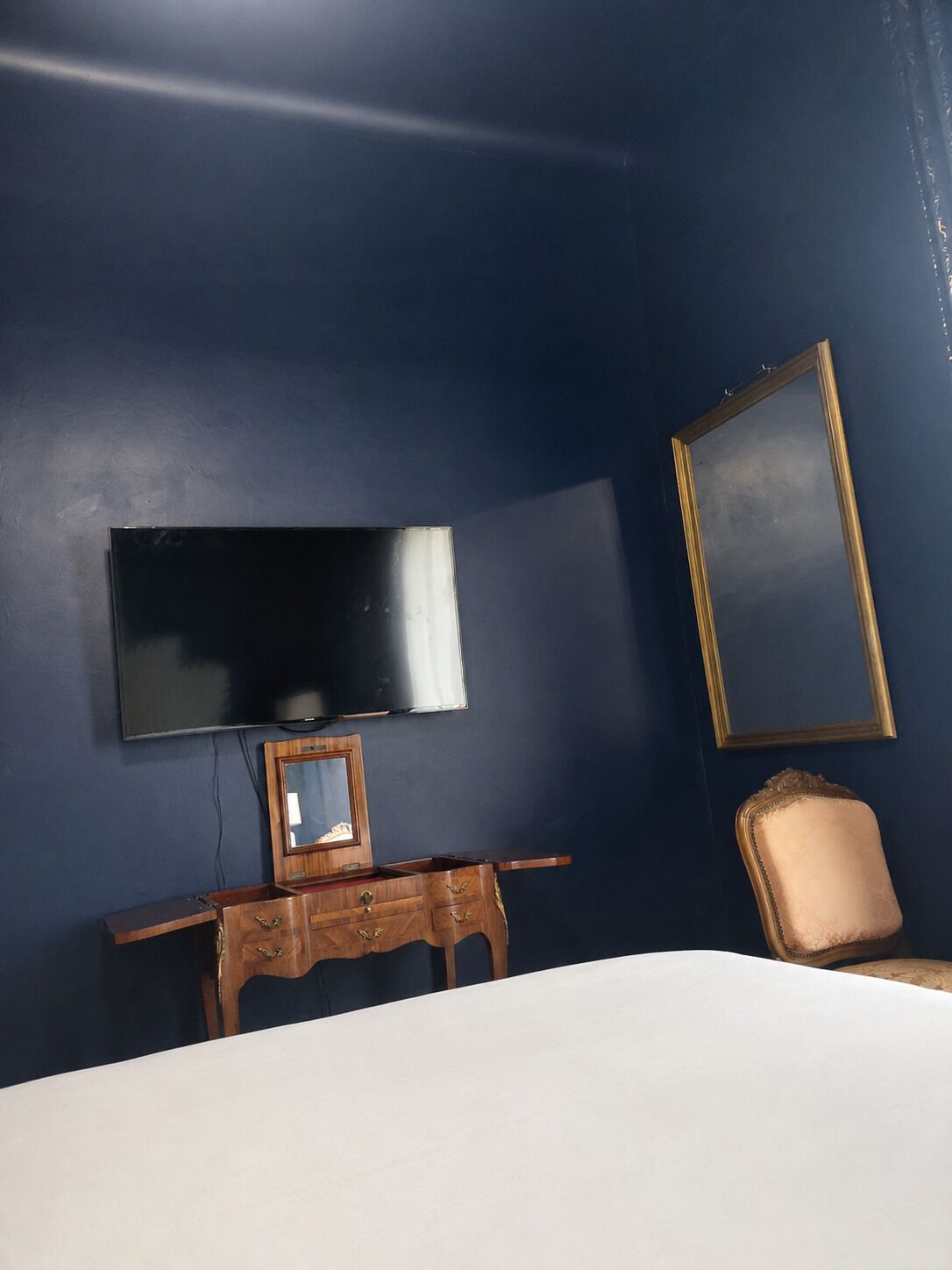 A room with a bed, a wooden dresser, a television, and two framed pictures on the wall.
