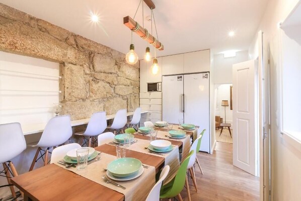 A dining area with a stone wall, wooden tables, and chairs. - PORTO CONCEPT HOME - PARANHOS (Porto)
