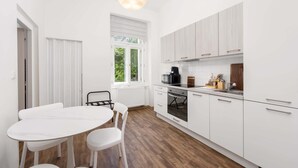 A modern kitchen with white cabinets, a dining table with chairs, and a pendant light. - Stylish Design Apartment in Central Prague (Hlavní město Praha)