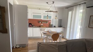 Una cocina moderna con armarios blancos, un comedor con mesa y sillas de madera, y una sala de estar con un sofá.