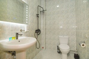 Un baño con lavamanos blanco, inodoro y zona de ducha.
