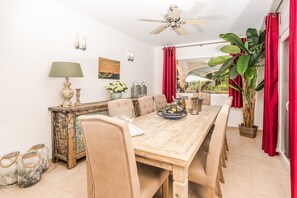 A dining area with a wooden table, chairs, a ceiling fan, and a potted plant. - Villa Los Almendros (Javea)
