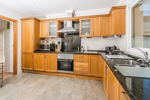Eine moderne Küche mit Holzschränken, Edelstahlgeräten und einem großen Fenster.