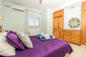 Ein Schlafzimmer mit einem Bett, einem Fenster, einem Holzschrank und einer Wanddekoration.