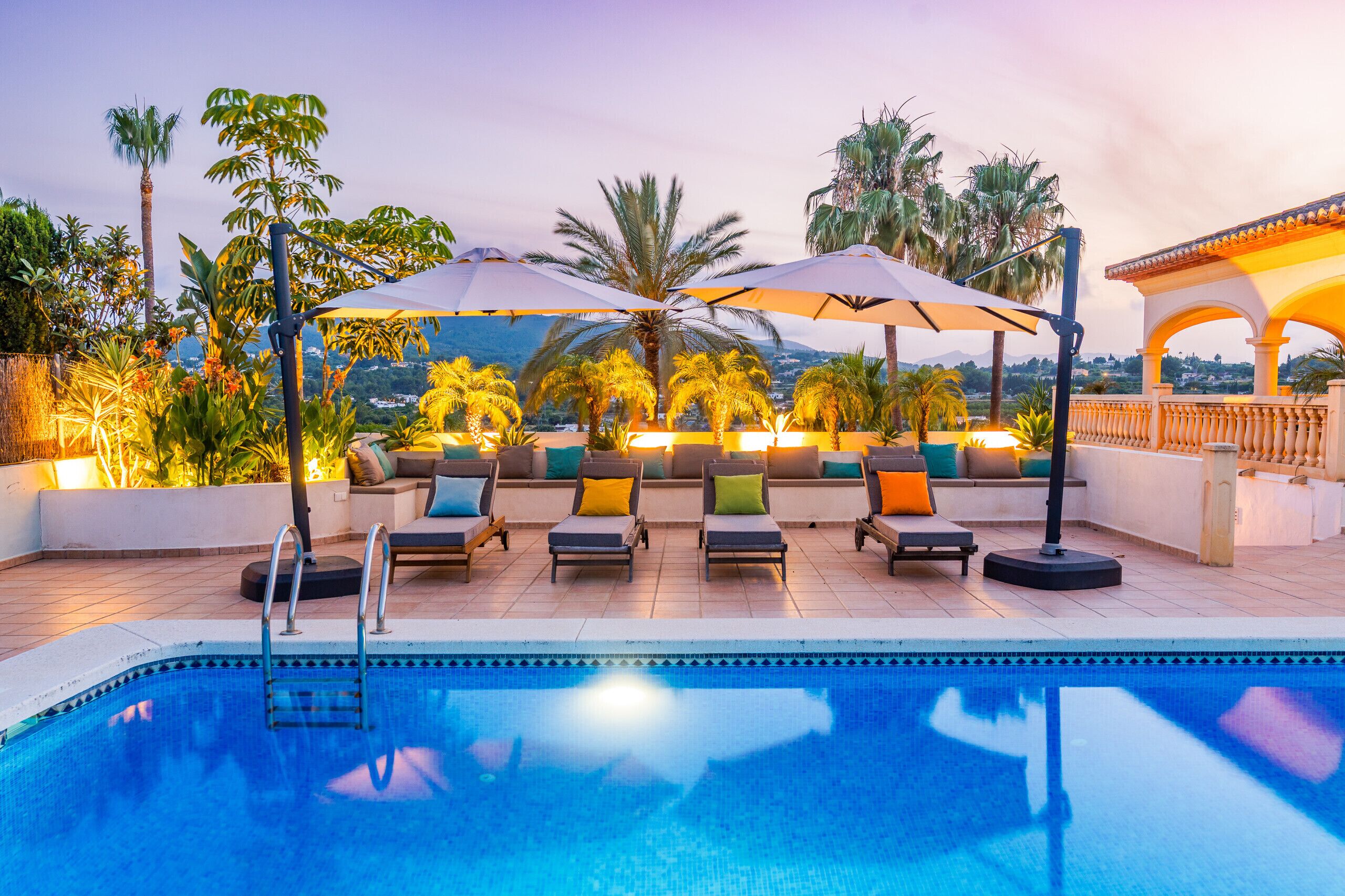 A poolside area with lounge chairs, umbrellas, and a view of the landscape.
