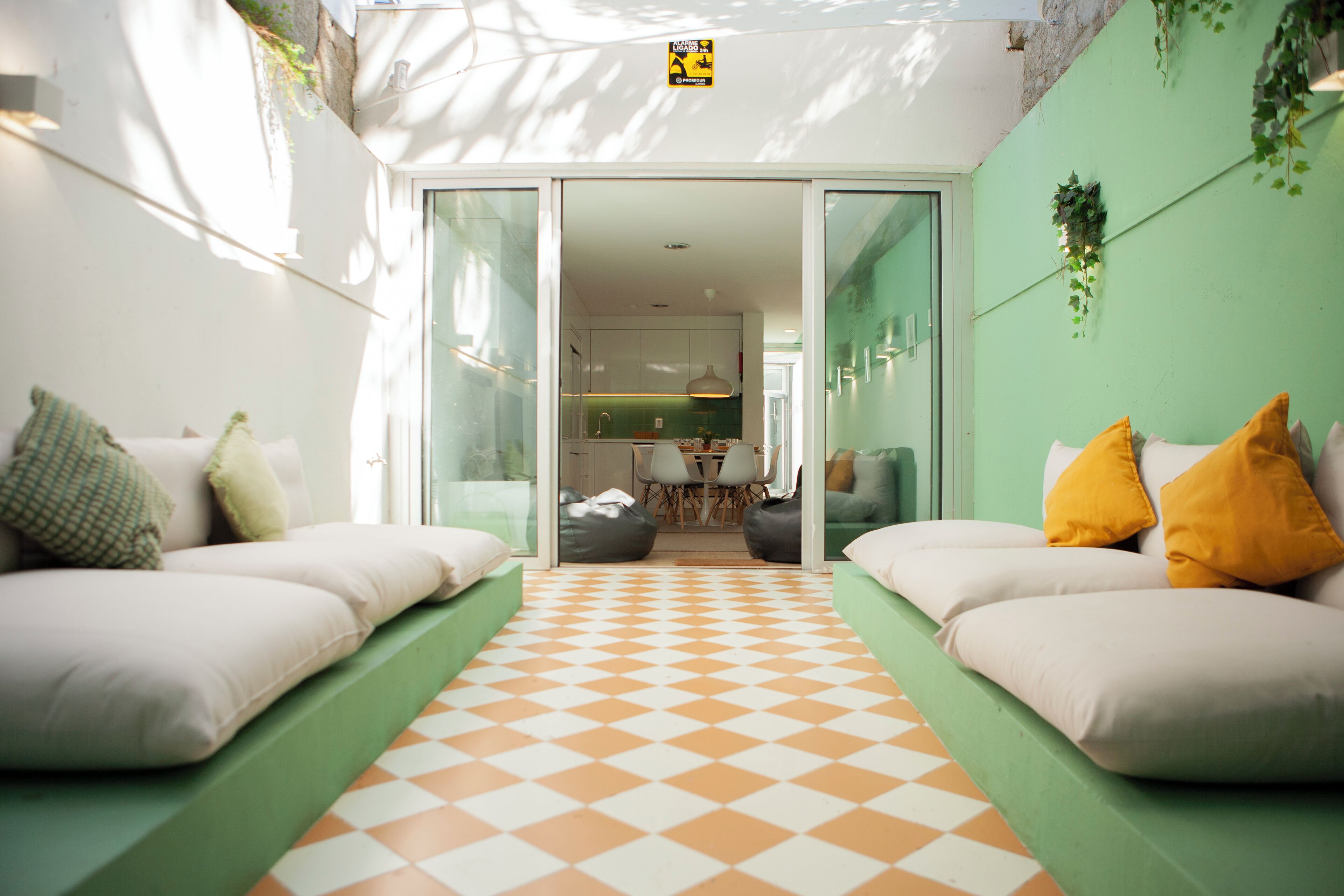 A modern interior with a checkered floor, green walls, and a view into a kitchen area.