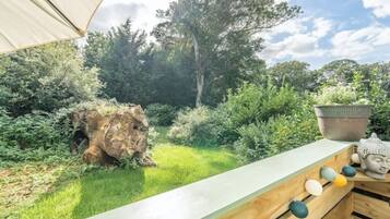 Een tuin met een houten bankje, een Boeddhabeeld en een bloempot.