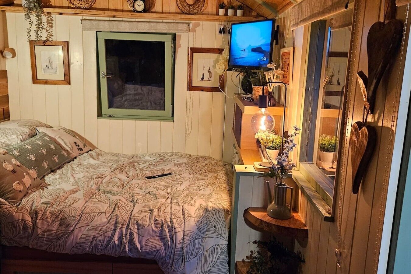 A cozy bedroom with a bed, a television, and a window.