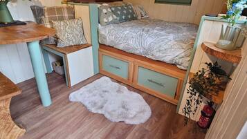 Una stanza accogliente con un letto, un tavolino, una panca e un tappeto morbido e bianco.