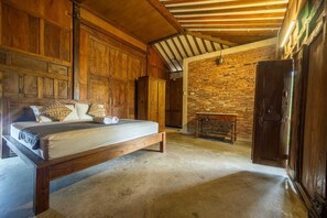 A wooden bed in a rustic room with exposed brick walls and a sloped ceiling. - Cozzy Villa Omah Nongko (yogyakarta)