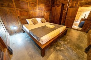 A wooden-paneled room with a bed, pillows, and a blanket. - Cozzy Villa Omah Nongko (yogyakarta)