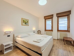 A hotel room with a single bed, bedside tables, a small desk, a radiator, and a window with curtains. - Locanda dei Nonni by Interhome (Riva del Garda)