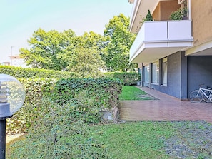 Ein modernes Gebäude mit Balkon, einem Fahrrad und einem gepflegten Garten.