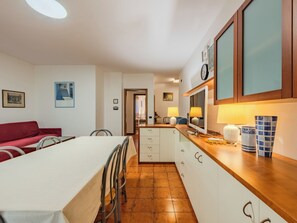 Une cuisine compacte avec une table à manger, des chaises, un canapé rouge et un téléviseur.