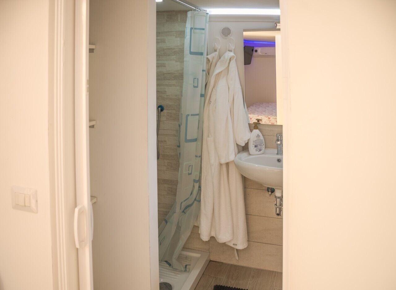 Un bagno con doccia, lavandino e porta asciugamani.