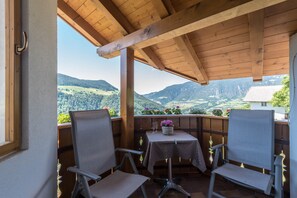 A covered outdoor seating area with two chairs and a table, overlooking a mountainous landscape. - Family-Friendly Apartment “Alpe Unterkehrhof” with Mountain View, Garden & Terrace (Lajen)