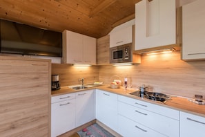 A modern kitchen with white cabinetry, a built-in microwave, a coffee maker, and a sink. - Family-Friendly Apartment “Alpe Unterkehrhof” with Mountain View, Garden & Terrace (Lajen)
