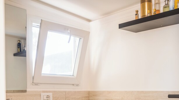 A bathroom with a toilet, bidet, sink, and a window above the toilet.