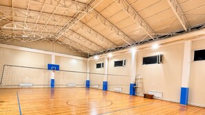 Um ginásio coberto com piso de madeira, aros de basquete e teto alto.