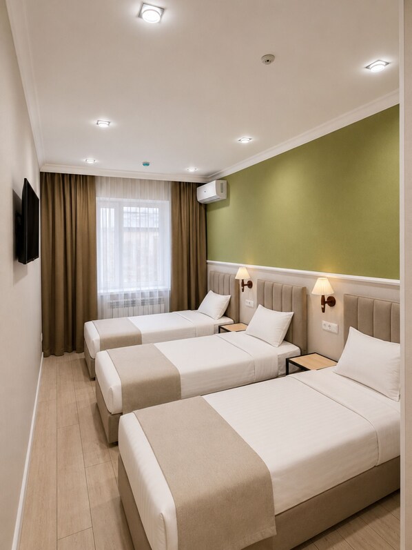 Habitación de hotel con dos camas, televisión, aire acondicionado y una ventana con cortinas.