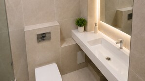 Uma casa de banho moderna com sanita, lavatório e zona de duche.