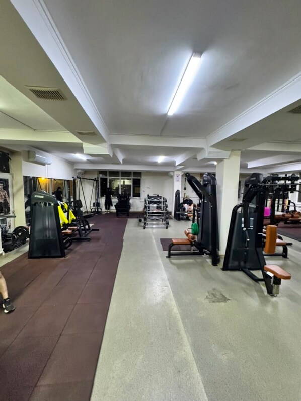 A gym with various exercise equipment, a running track, and a person walking. - Aqua Hotel (Bishkek)