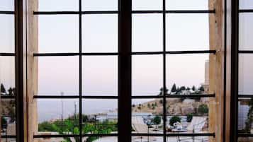 A window with a grid pattern, through which a patio area with chairs and a potted plant is visible.
