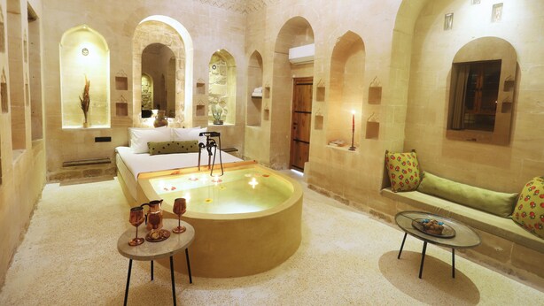 Un cuarto de spa con una bañera grande, un sofá y una mesita con velas.