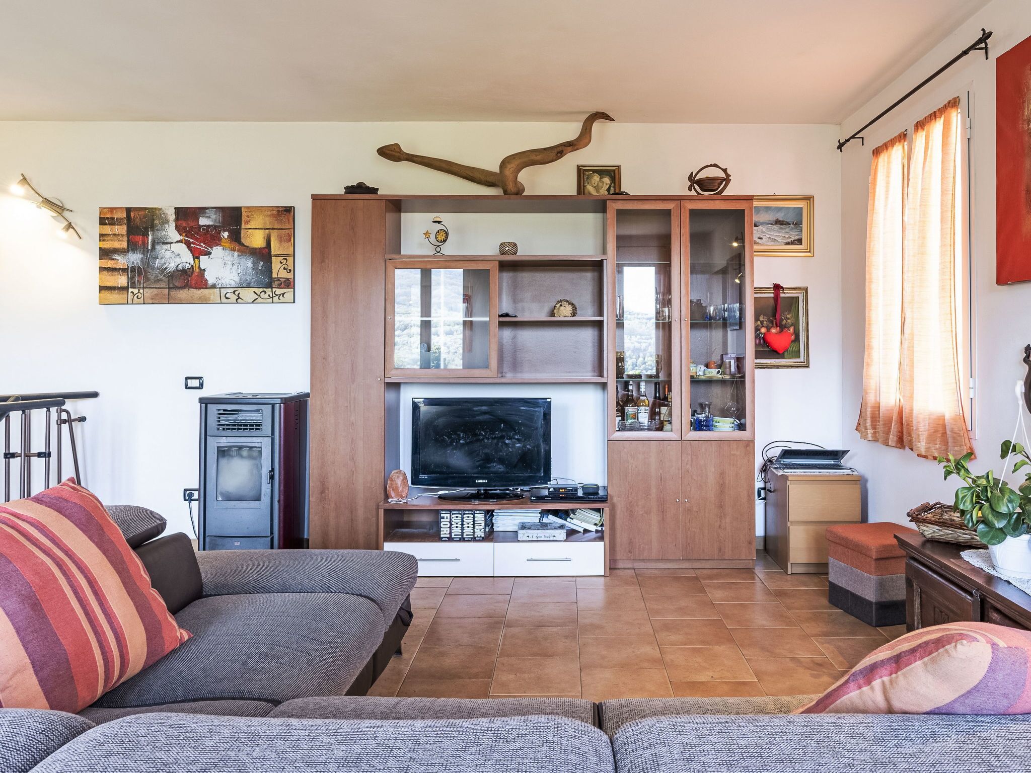 Un salon avec un canapé, un téléviseur, un meuble en bois et des œuvres d’art accrochées au mur.