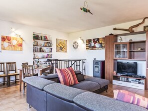 Ein modernes Wohnzimmer mit einer Eckcouch, einem Essbereich und einem TV-Schrank.