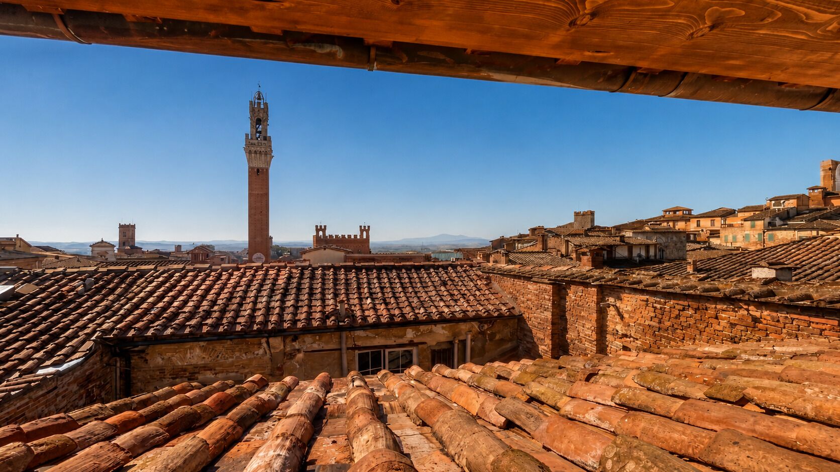 A view of a historic town with terracotta roofs, a prominent tower, and traditional architecture.