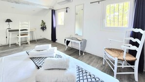 A hotel room with a bed, a desk, a chair, a mirror, and a window with curtains. - Le Repos House—Sleeps 6—Pool—Pétanque (Alleins)