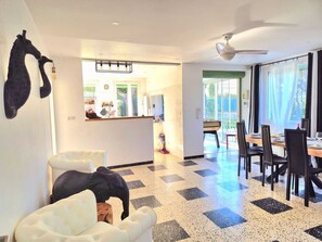 A spacious living area with a checkered floor, a dining table set for four, and a large window providing natural light. - Le Repos House—Sleeps 6—Pool—Pétanque (Alleins)