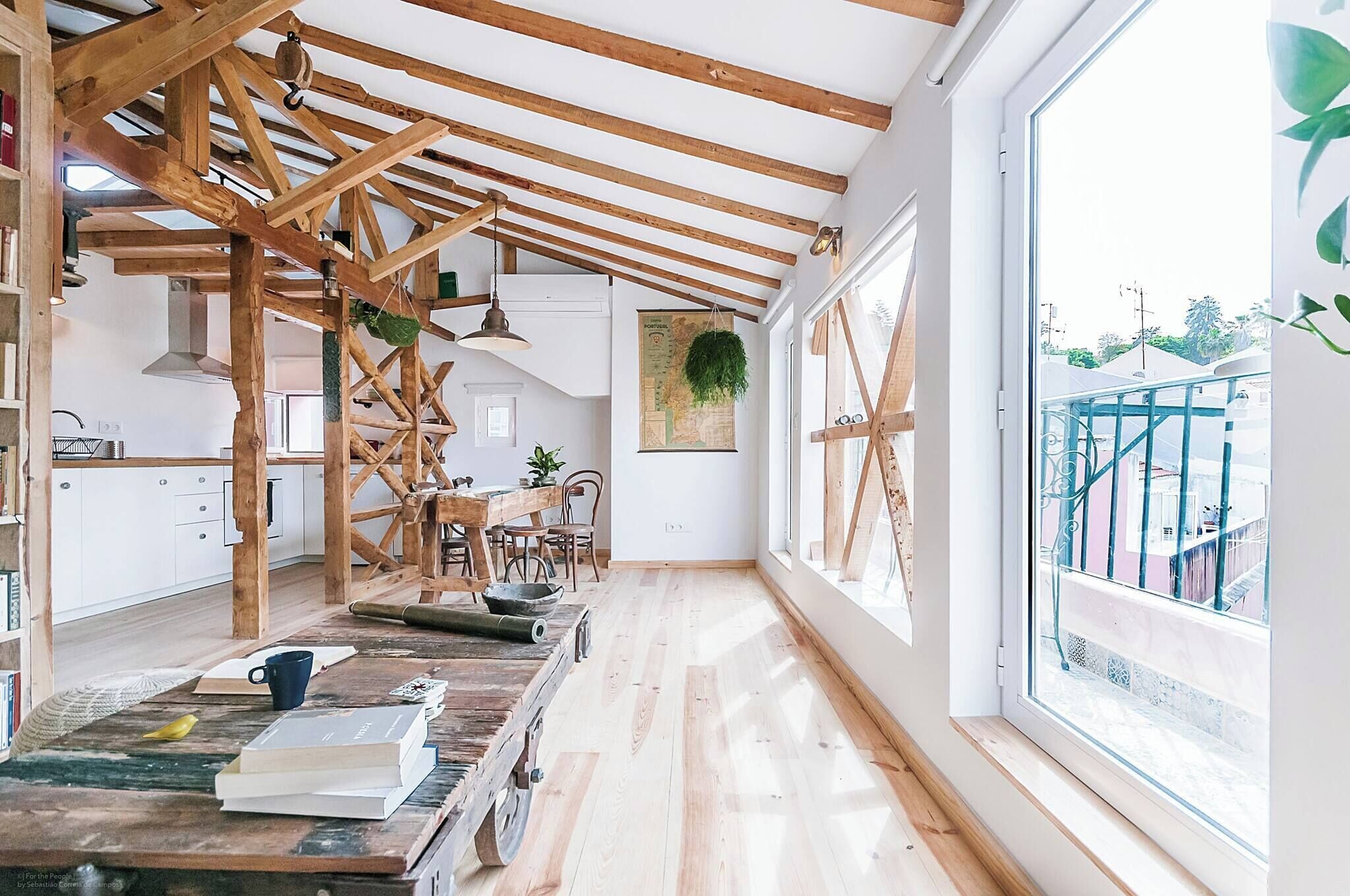 A spacious kitchen with wooden beams, a large window, and a view of the outside.