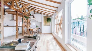 A spacious kitchen with wooden beams, a large window, and a view of the outside.