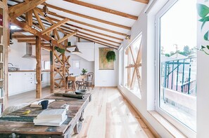 Eine geräumige Küche mit Holzbalken, einem großen Fenster und Blick ins Freie.