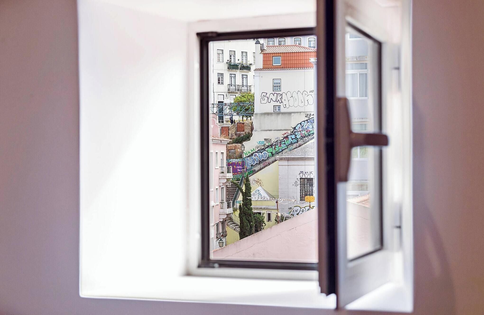 A window with a view of a building with graffiti and a staircase.