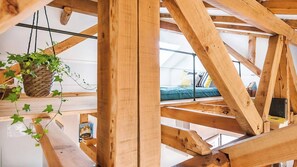 A wooden truss structure, a hanging plant, and a bed with pillows. - Balcony to Central Garden w AC - Vintage Library (Lisbon)