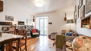 A spacious living area with a dining table, chairs, a sofa, and a bookshelf. - Charming Mouraria Apartment With Private Terrace in Lisbon (Lisbon)