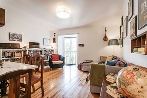 A spacious living area with a dining table, chairs, a sofa, and a bookshelf. - Charming Mouraria Apartment With Private Terrace in Lisbon (Lisbon)