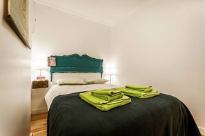 A bed with a teal headboard, white bedding, and green towels. - Charming Mouraria Apartment With Private Terrace in Lisbon (Lisbon)