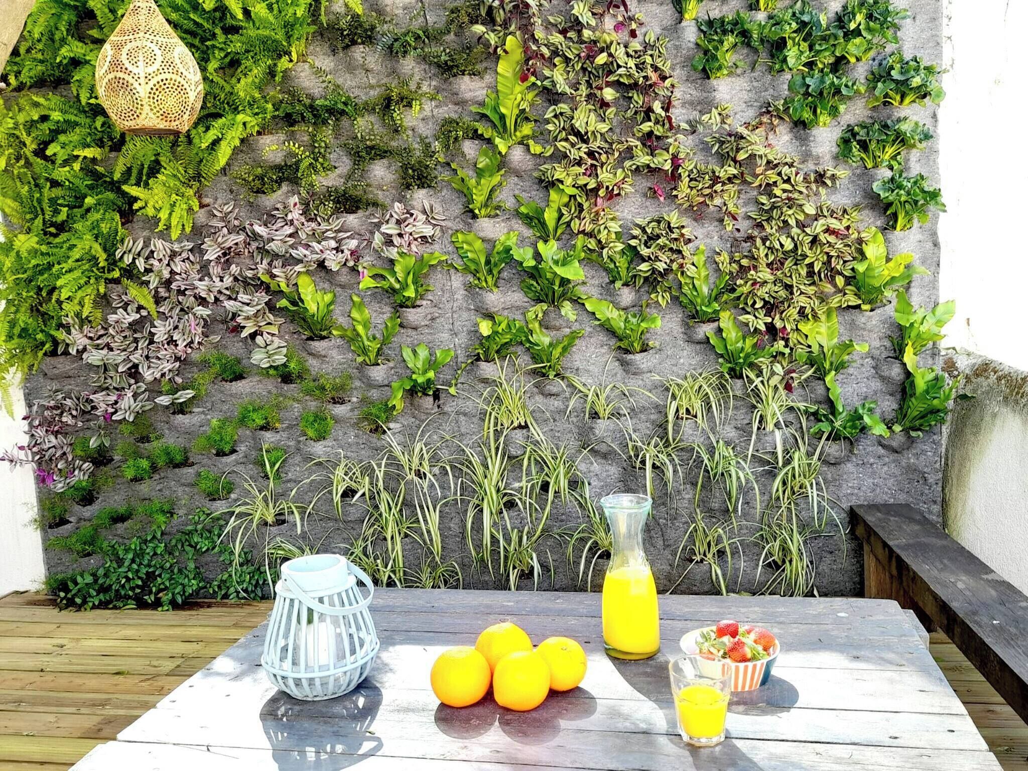 A wooden table with a white pitcher, a glass of orange juice, and a bowl of fruit.