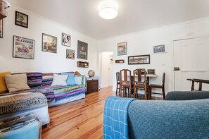 A cozy living room with a sofa, a coffee table, and a dining area with chairs and a table. - Charming Mouraria Apartment With Private Terrace in Lisbon (Lisbon)