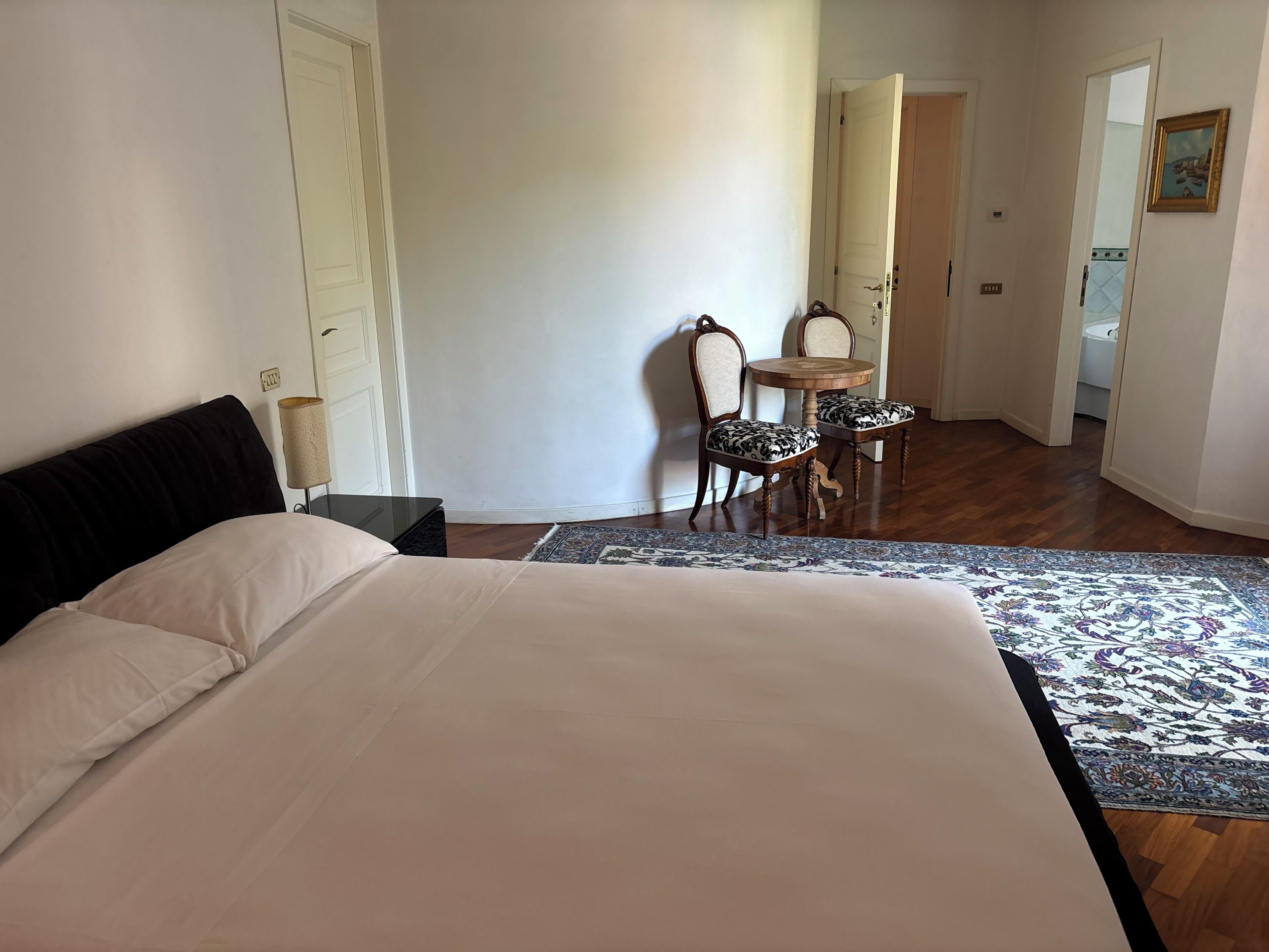 Une chambre à coucher comprenant un lit, une table de chevet, une chaise, une table et un tapis à motifs.