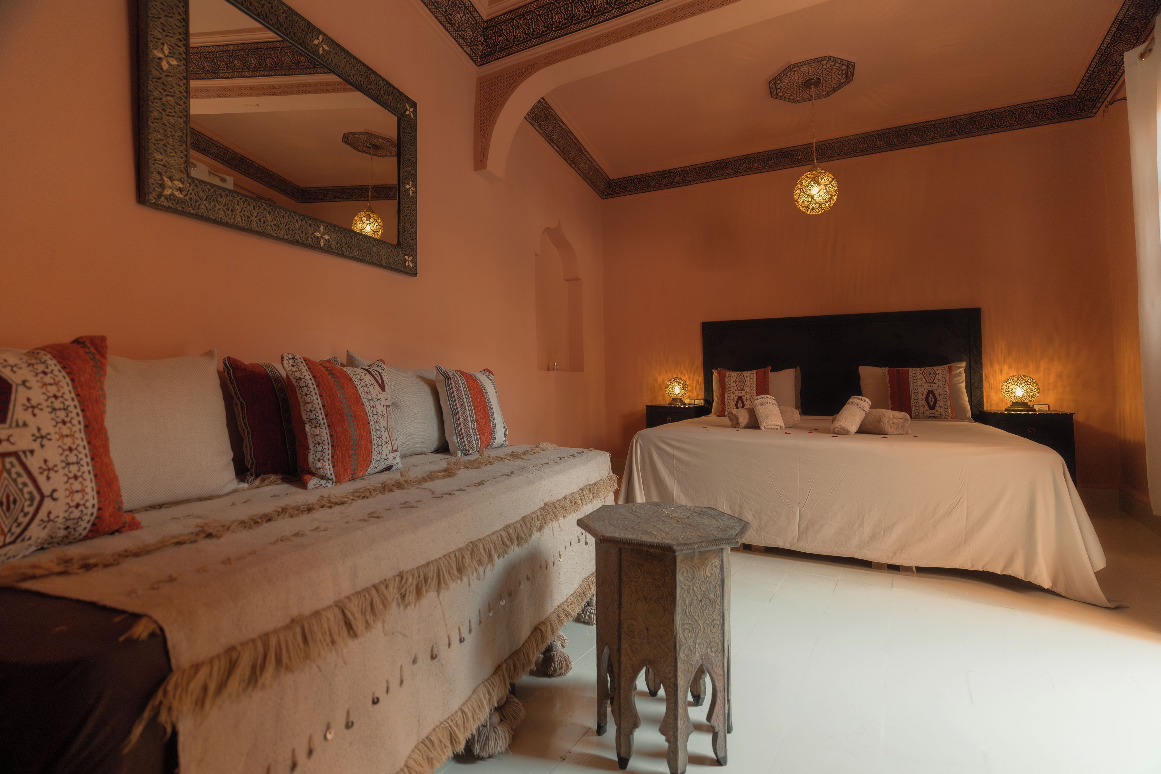 A bedroom with two beds, a large mirror, and a small table.