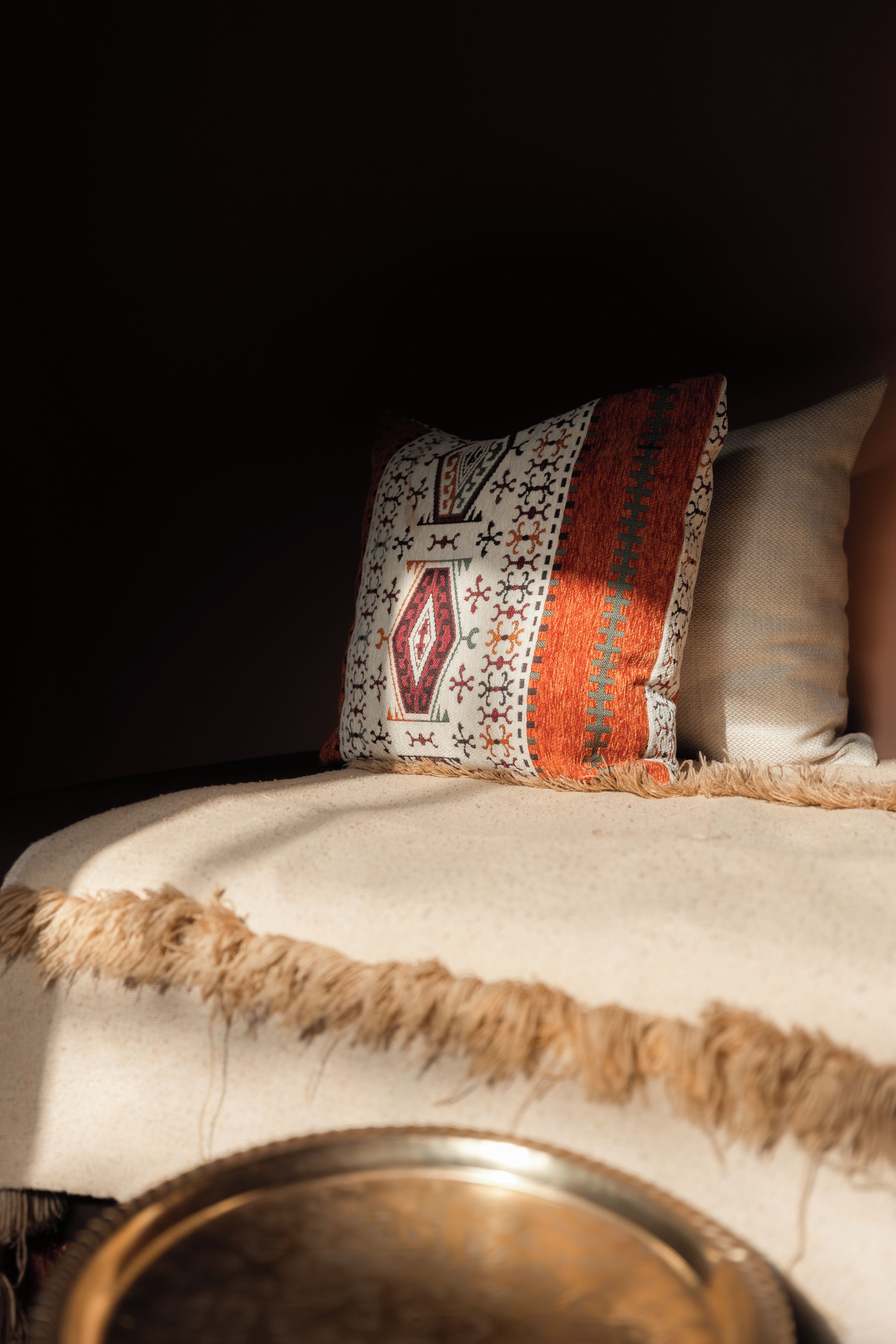 A bed with a patterned pillow and a textured blanket.