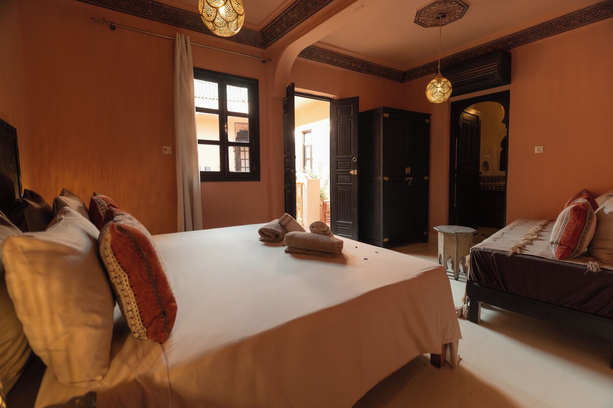 A hotel room with a large bed, a smaller bed, a wardrobe, and a bathroom.