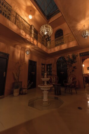 A spacious atrium with a central fountain, ornate railings, and multiple light fixtures. - Riad Hima by Assila (Marrakech)
